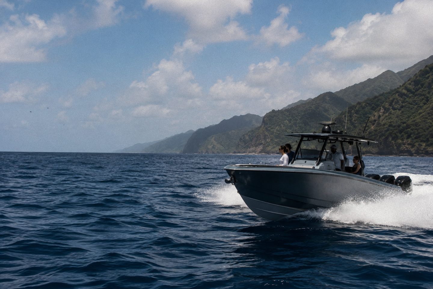 A powerboat running along the Saint Vincent coastline, mountains rising behind, guests aboard