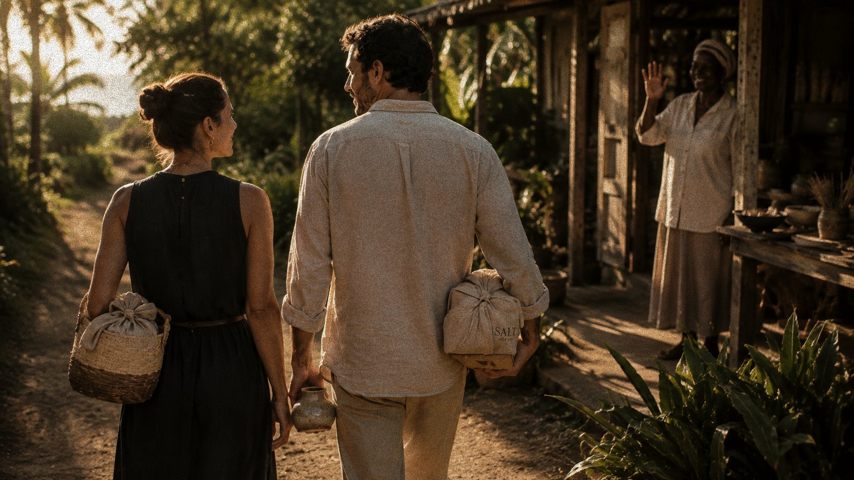 A couple walking away from the workshop at golden hour, carrying their finished woven pieces, the maker waving behind them